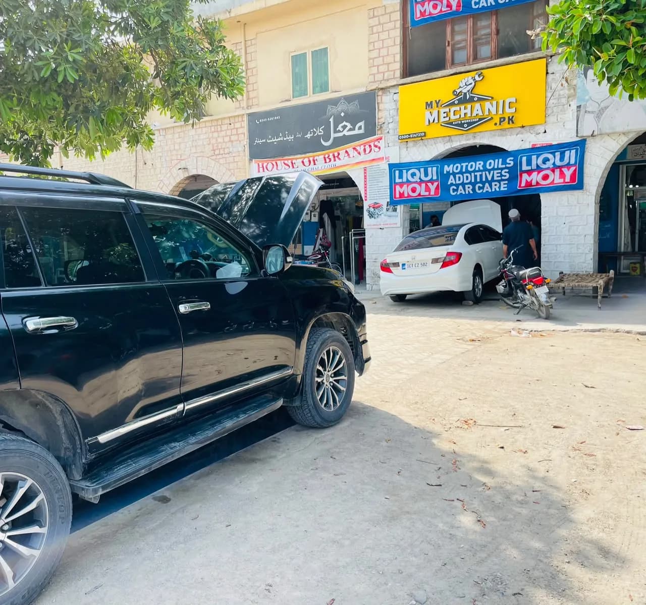 Black SUV with its bonnet open in front of the My Mechanic workshop