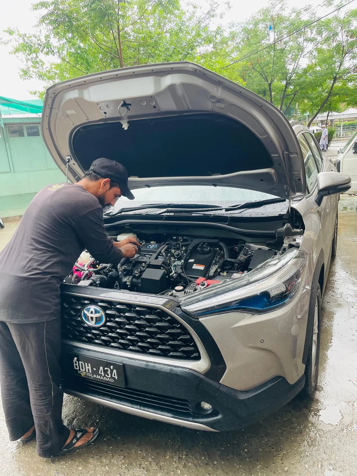 My Mechanic technician inspecting the engine bay of a Toyota Corolla Cross hybrid with the bonnet open