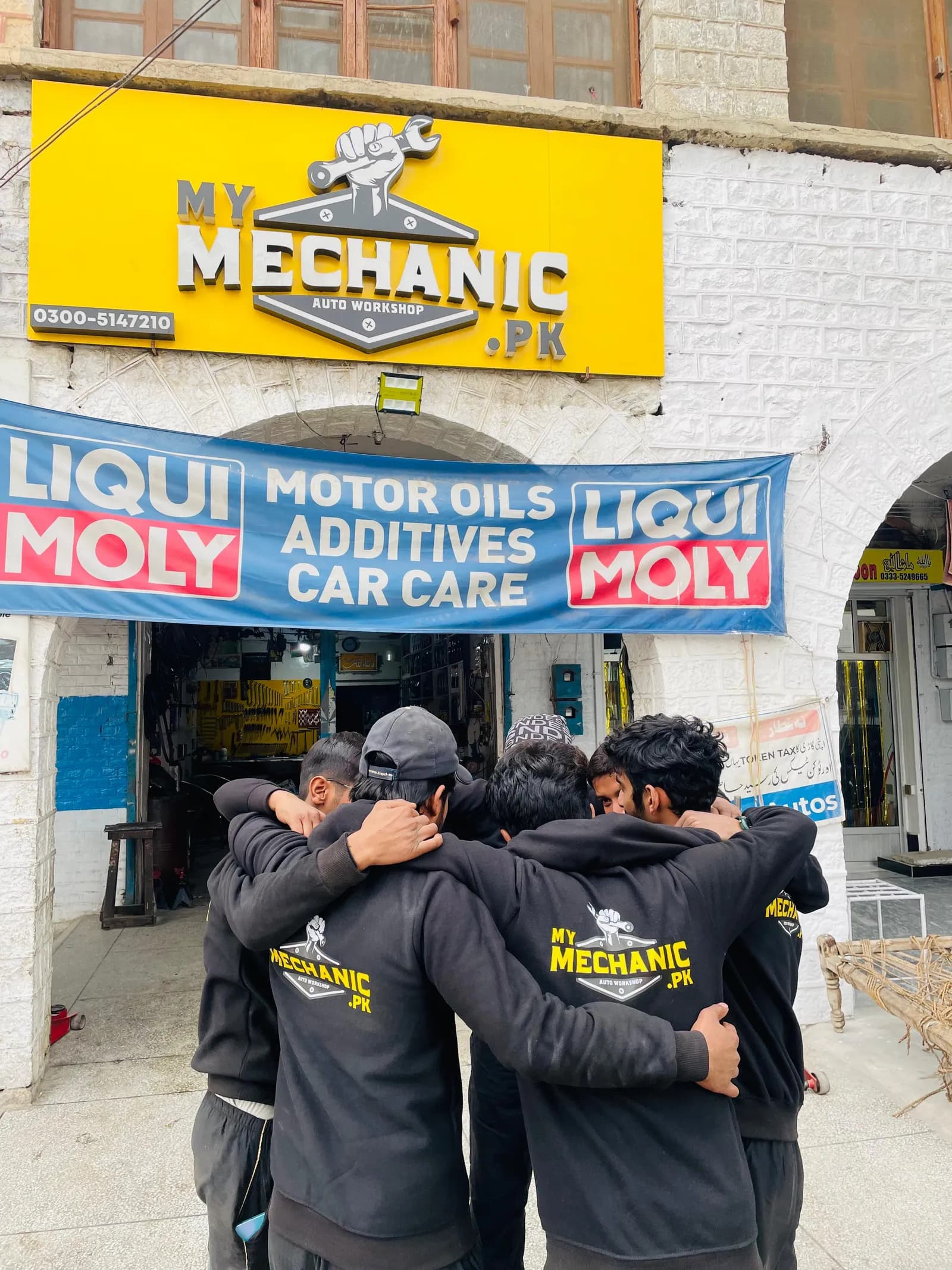 My Mechanic technicians in a team huddle outside the workshop, arms around each other